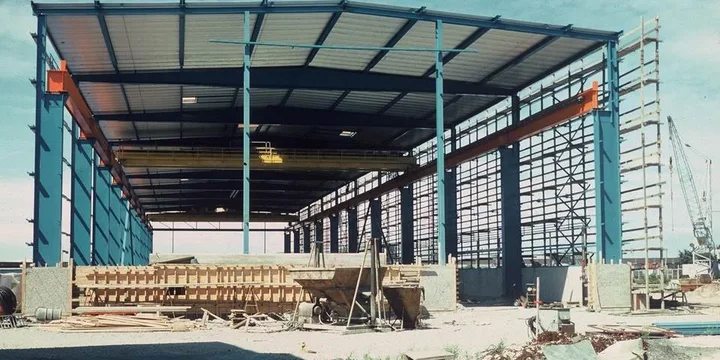 Stålstomme till industrihall under uppförande, med travers monterad under takbalken